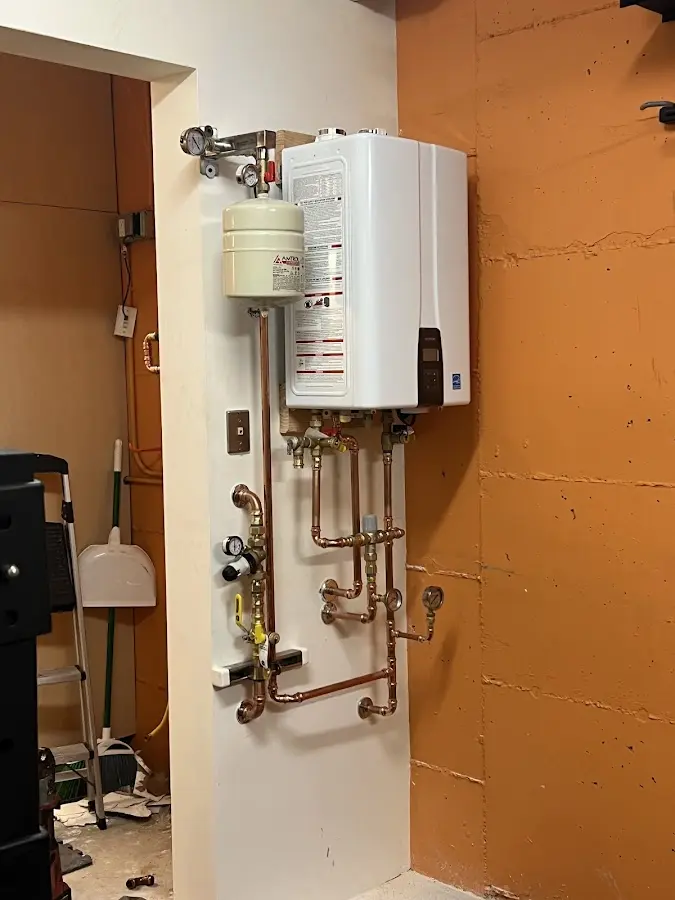 Plumbing technician inspecting water heater connections in Coldwater